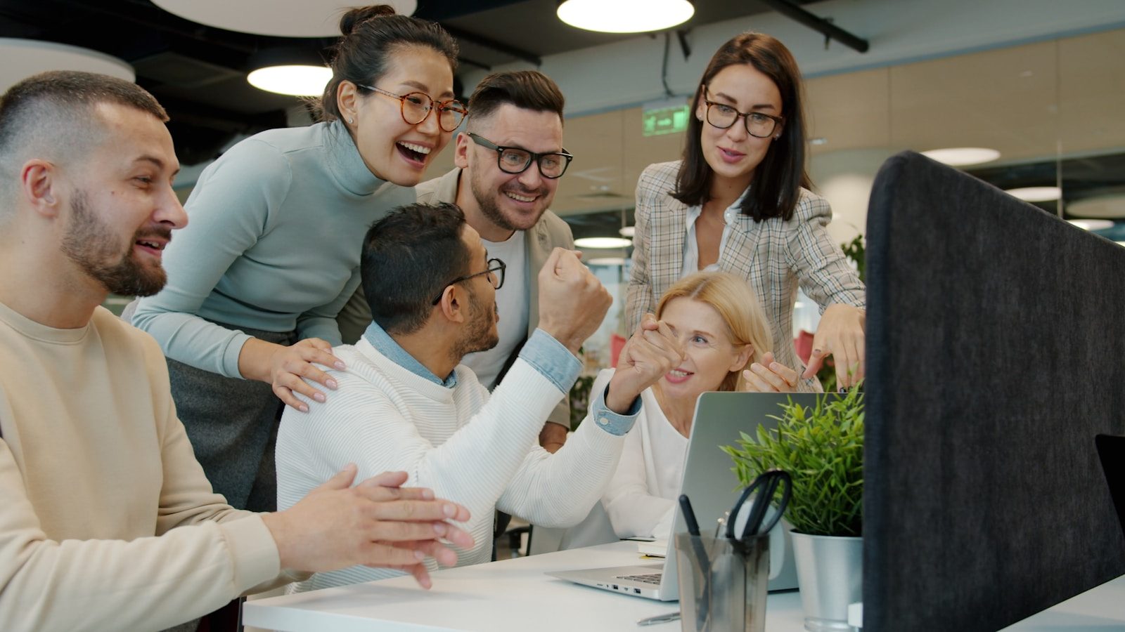 Collaborative team celebrating progress around a computer